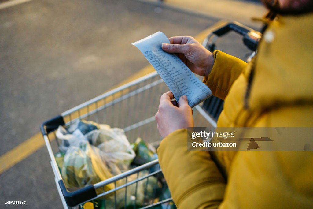 Young Woman Looking At The Receipt From The Grocery Store