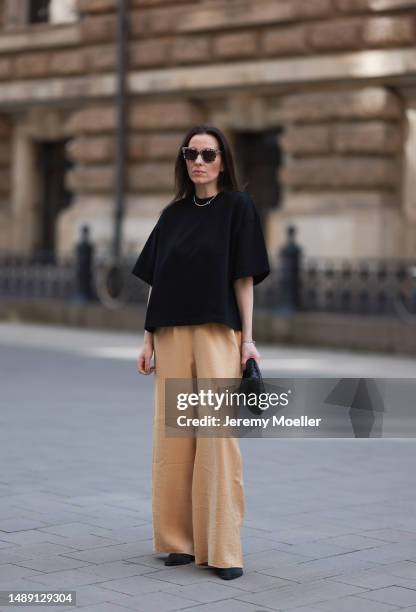 Elise Seitz seen wearing a Bottega Veneta Jodie black leather bag, Isabel Marant black boots, Soho Studios black shirt and beige and brown pants and...