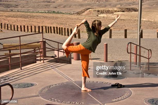 woman doing the lord of the dance yoga pose atop the four corners monument. - four corners monument stock pictures, royalty-free photos & images