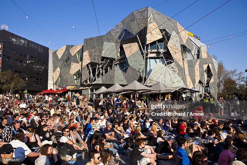 Australian Rules Football supporters watching game on screen in Federation Square.