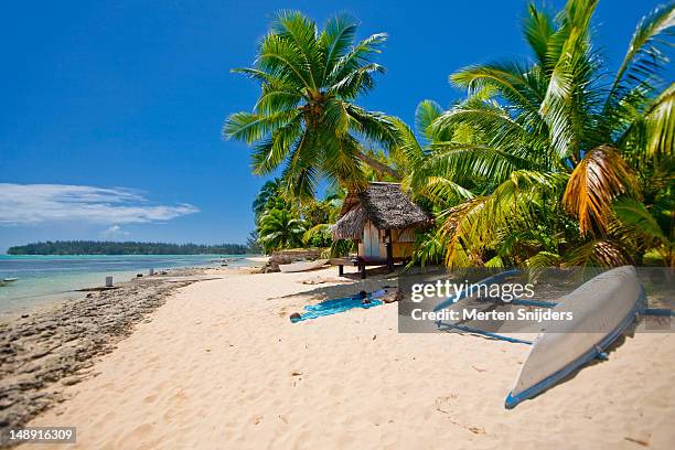 small polynesian style beach hut under palmtrees, with upturned outrigger on beach. - french polynesia stock-fotos und bilder