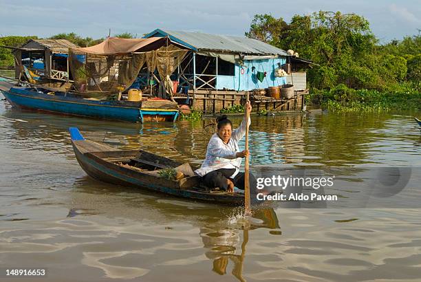 woman paddling past floating houses on tonle sap lake. - chong kneas - fotografias e filmes do acervo