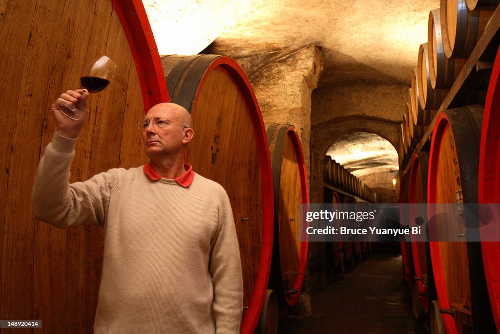Owner of Conti Sertoli Salis Winery checking quality of wine in Sertoli Salis Palace wine cellar.