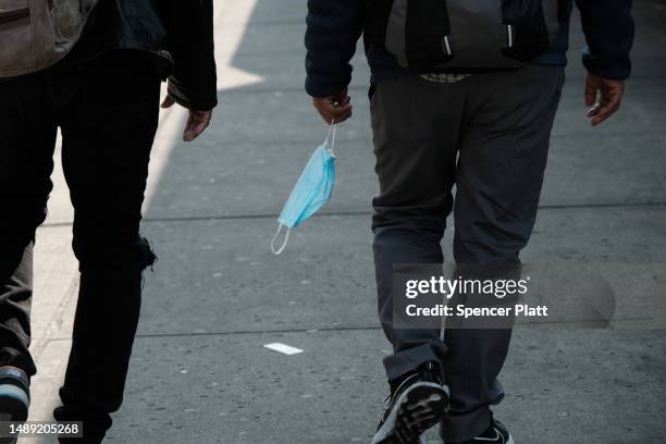 Man carries a mask as he walks along Roosevelt Avenue, which passes through the neighborhoods of Elmhurst, Corona and Jackson Heights, areas that...