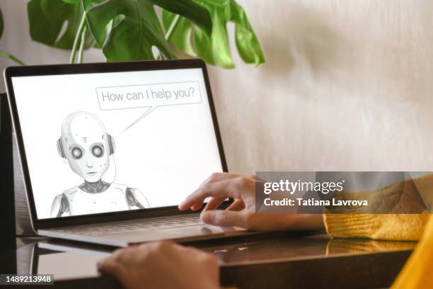 woman in yellow uses her laptop for communication with text bot. artificial intelligence on the screen is ready to help. future technologies, science, machine learning conceptual photo - chatbots stock pictures, royalty-free photos & images