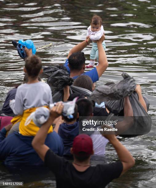 Mth old baby is held up as migrants swim cross the Rio Grande as they try to enter the United States on May 11, 2023 in Matamoros, Mexico. A surge of...