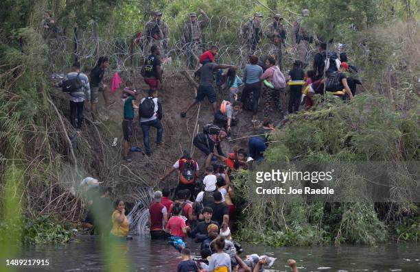 Migrants speak with members of the Texas National Guard and other law enforcement officials after crossing the Rio Grande to try and enter the United...