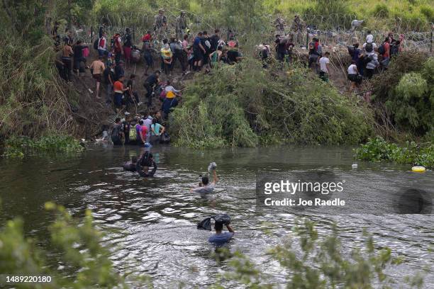 Migrants cross the Rio Grande as they try to enter the United States as members of the Texas National Guard and other U.S. Law enforcement officials...
