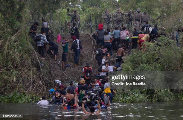 Migrants speak with members of the Texas National Guard and other law enforcement officials after crossing the Rio Grande to try and enter the United...