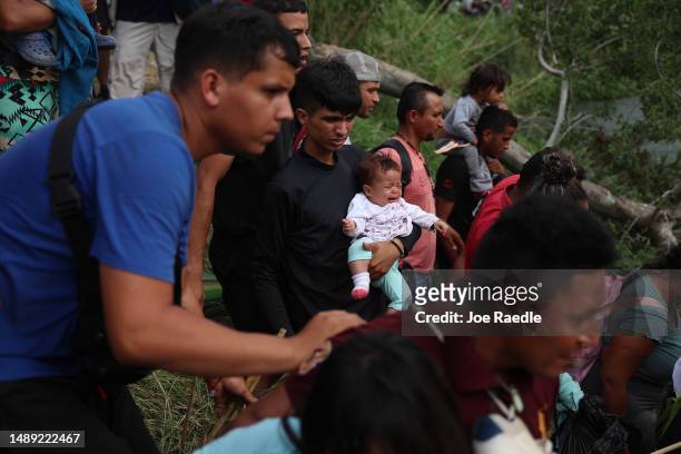 Migrants walk into the Rio Grande from the bank of the river as they cross to enter the United States on May 11, 2023 in Matamoros, Mexico. A surge...