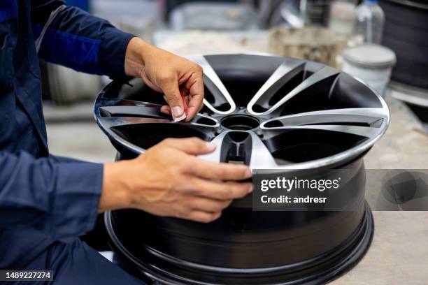 close-up on a man sanding an alloy wheel at a car part factory - jante em liga leve imagens e fotografias de stock