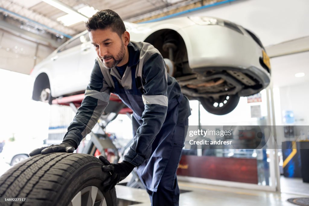 Mecánico feliz cambiando un neumático pinchado en un automóvil