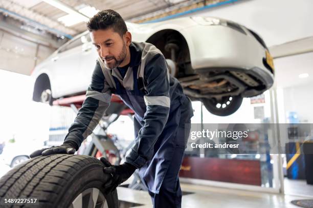 happy mechanic changing a flat tire on a car - carrying stock pictures, royalty-free photos & images