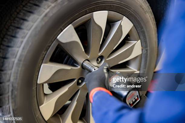 車のパンクしたタイヤを交換する整備士 - wheel rim ストックフォトと画像