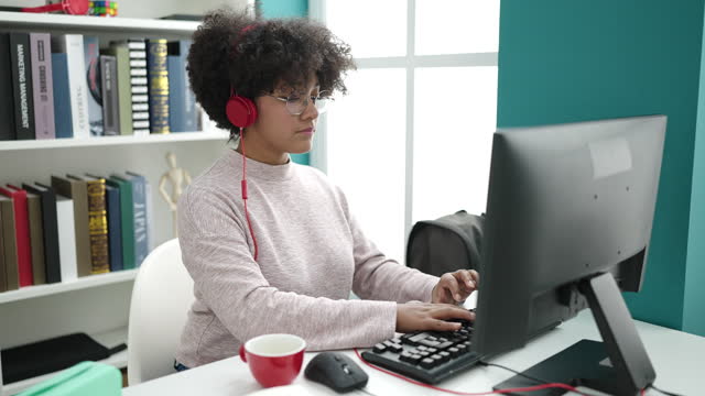 Young african american woman student using computer drinking coffee at university classroom