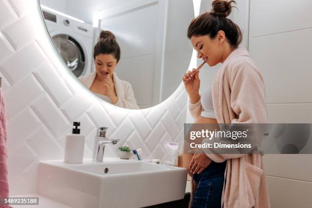 cheerful pregnant woman brushing teeth. - brushing teeth stock pictures, royalty-free photos & images