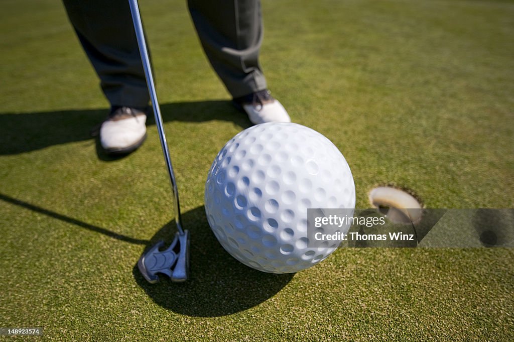 Man playing golf with oversized ball.