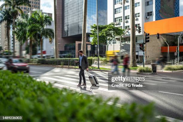 mature businessman crossing the street holding a suitcase - avenida paulista stockfoto's en -beelden
