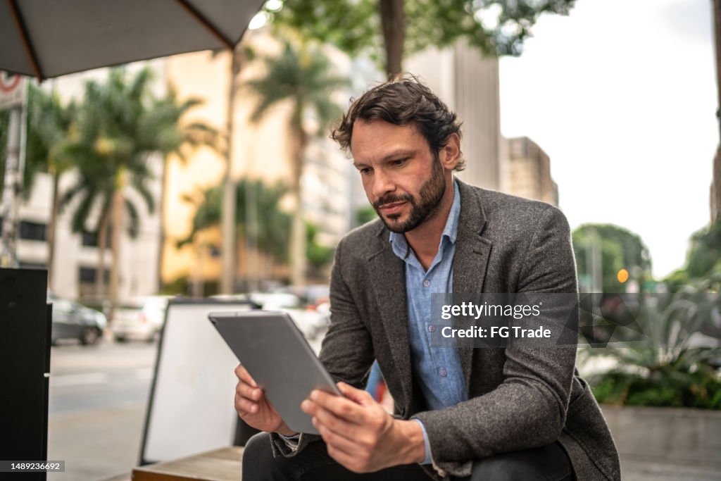 Mature man using the digital tablet in the street