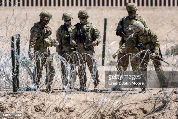 Texas National Guard soldiers close a section of razor wire surrounding a makeshift migrant camp on May 11, 2023 in El Paso, Texas. The number of...