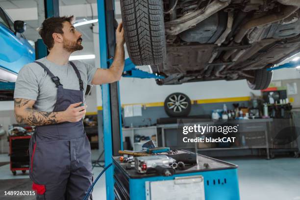 auto mechanic working at car service - undercarriage stock pictures, royalty-free photos & images