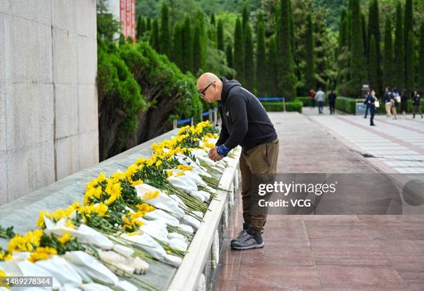 Man lays flowers to mourn for victims at the ruins of Xuankou Middle School, now a memorial site for the 2008 Wenchuan earthquake, on May 11, 2023 in...