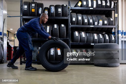 Mechanic changing a flat tire and carrying a wheel at a repair garage Mechanic changing a flat tire and carrying a wheel at a repair garage
