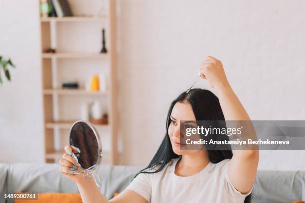 lady looks in the mirror and applies the serum on the scalp and hair from the pipette - receding stock pictures, royalty-free photos & images