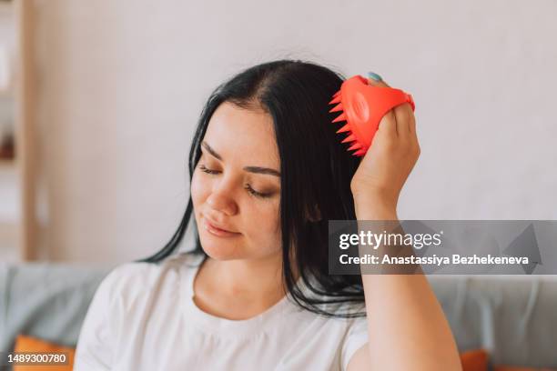 lady gives herself head massage with scalp massager - human scalp stock pictures, royalty-free photos & images