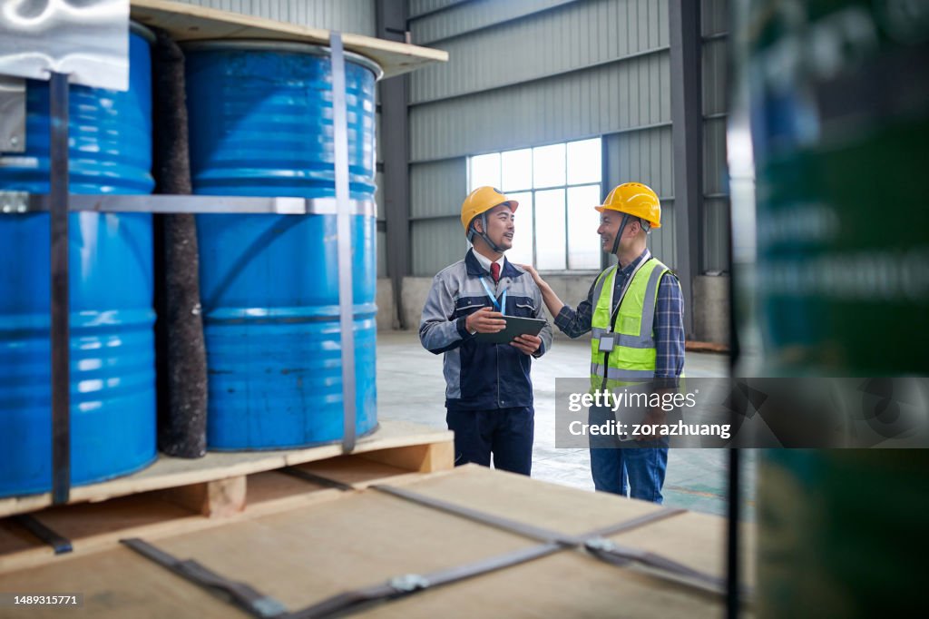 Zwei asiatische Männer untersuchen und diskutieren im Chemikalienlager