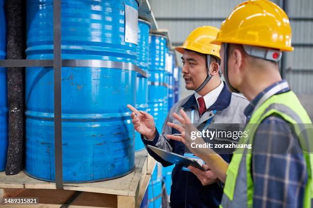 dos hombres asiáticos examinando y discutiendo en un almacén de productos químicos - hazmat fotografías e imágenes de stock