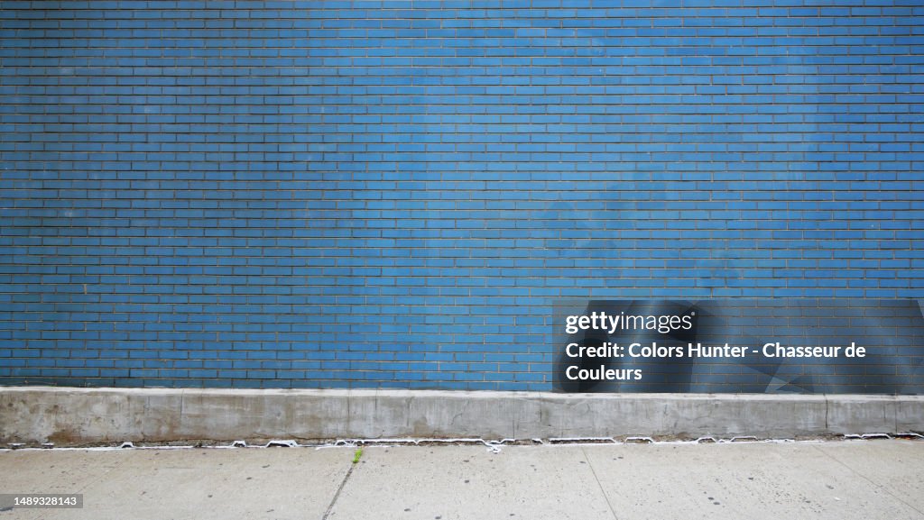 Empty blue brick wall and cement sidewalk in Manhattan, New York, United States