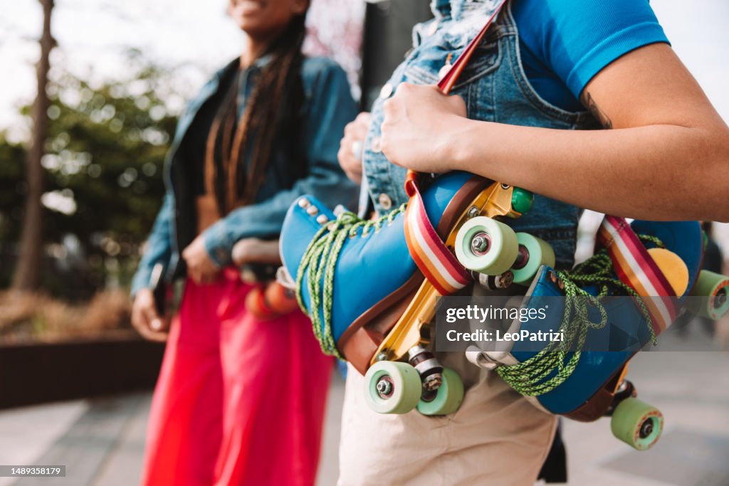 Two friends walking bringing roller skates on shoulder