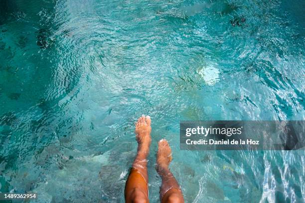 top view of woman playing with water with legs and feet in swimming pool. copy space. vacation and summertime - legs in water fotografías e imágenes de stock