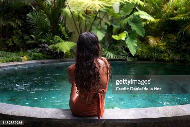 rear view of young female of color relaxing in the swimming pool on tropical vacation resort. copy space. summer vacation - bali luxury stock pictures, royalty-free photos & images