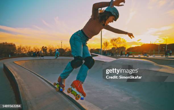 young stylish funky girl riding roller skates and doing tricks during idyllic sunset at skateboard park - roller skating stock pictures, royalty-free photos & images