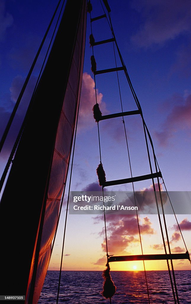 Sail & ladder on yacht silhouetted at sunset on  Caribbean Sea off St Barts.