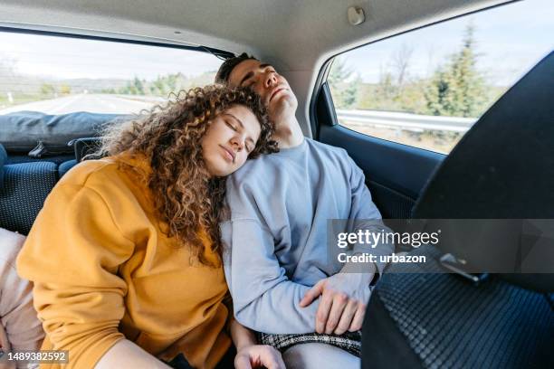 pareja joven durmiendo en el asiento trasero del coche - sleeping in car fotografías e imágenes de stock