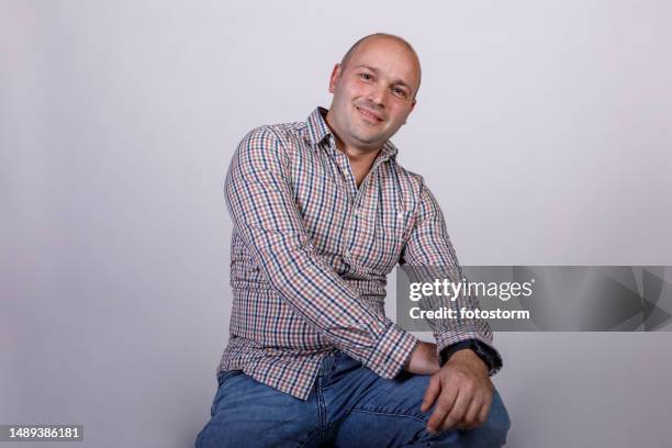 homem adulto médio confiante sentado contra o fundo branco, sorrindo para a câmera - homens de idade mediana - fotografias e filmes do acervo