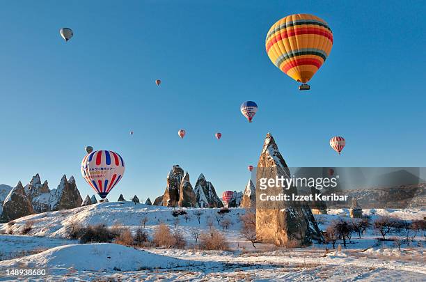 hot air balloons over snow covered rock formations. - turkey middle east stock-fotos und bilder