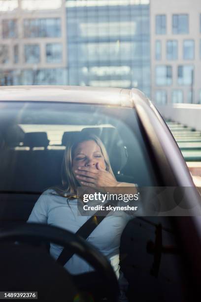 tired businesswoman yawning while driving a car. - tired driver stock pictures, royalty-free photos & images