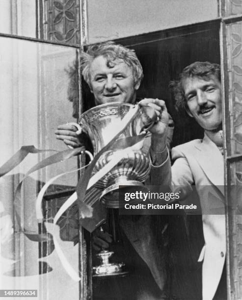 British football manager and former footballer Tommy Docherty, Manchester United manager, holds the FA Cup, alongside the Manchester United...