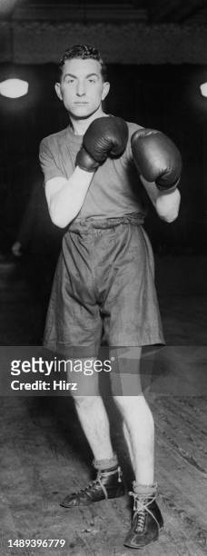British bantamweight boxer LV Burton, of the Mildway Boxing Club, wearing dark shorts, a dark t-shirt and boxing gloves, assumes his fighting stance,...