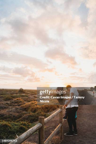 father and young child watching sunset at fuerteventura beach - family sports centre laughing stock pictures, royalty-free photos & images