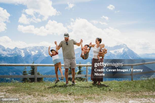 family having fun jumping in summer on mountain top alps - oberbayern photos et images de collection