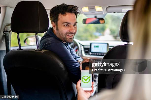 male rideshare driver receives mobile payment from his passenger - sharing economy stockfoto's en -beelden