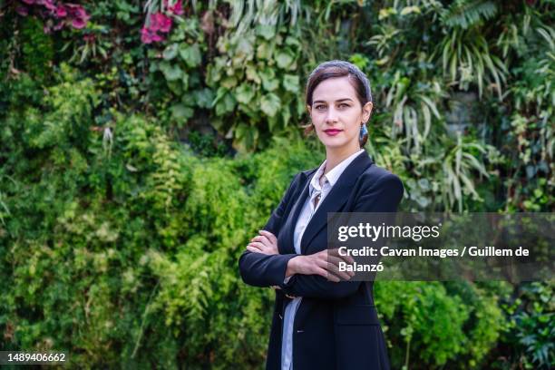 elegant young businesswoman looking at camera while standing in park - formal garden - fotografias e filmes do acervo