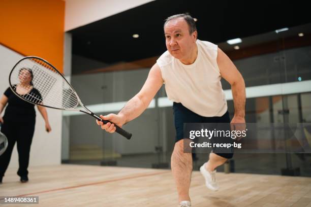 aktives seniorenpaar, das squash spielt - squash racquet stock-fotos und bilder