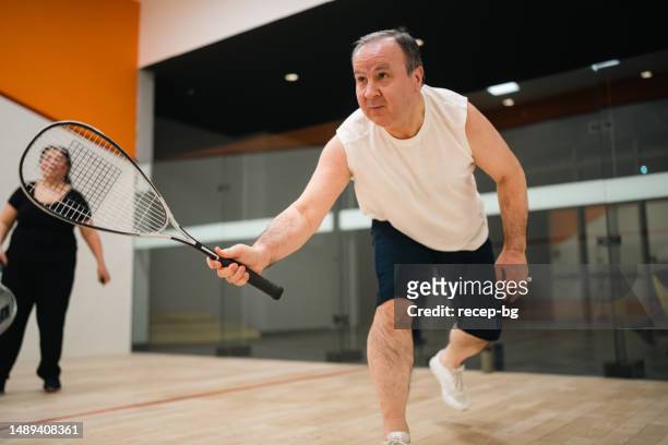 pareja senior activa jugando squash - squash fotografías e imágenes de stock