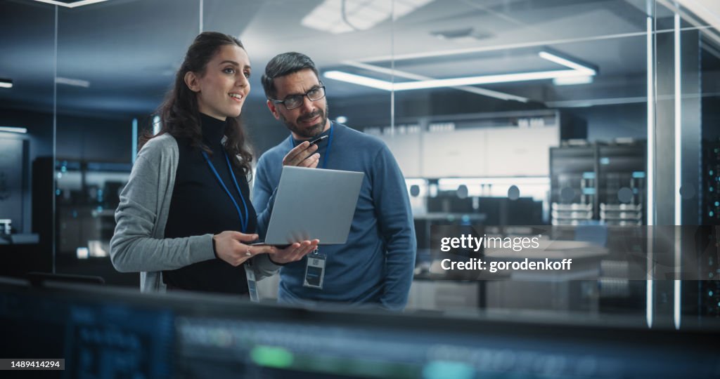 Portrait Of Two Happy Female And Male Engineers Using Laptop Computer ...